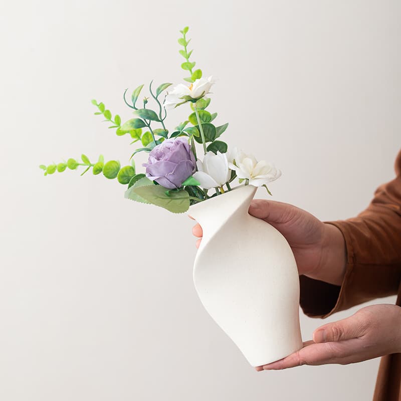 Folded stoneware ceramic vase held with flowers